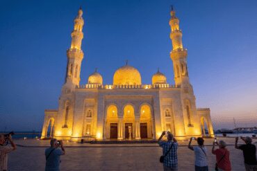 Illuminated Al Mina Mosque in Hurghada at twilight, showcasing Islamic architecture and minarets.