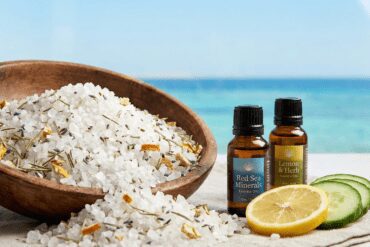 Natural Red Sea salt scrub in a wooden bowl with essential oils, set against a beach background, representing organic spa treatments in Hurghada.