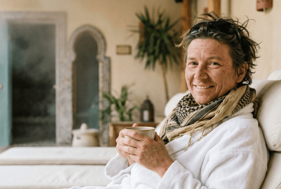 Traveler with a dusty desert scarf relaxing in a bathrobe and drinking herbal tea in a luxury spa after a desert safari in Hurghada.